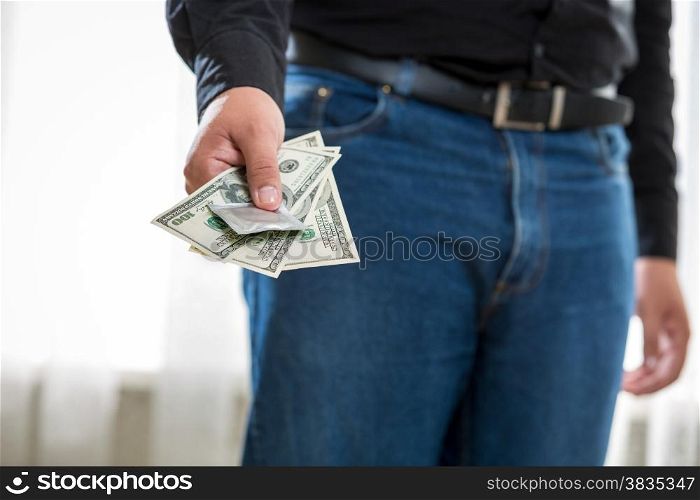 Closeup photo of young man holding pack of dollars and condom
