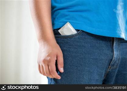 Closeup photo of young man in jeans with condom in pocket