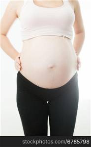 Closeup photo of young pregnant woman in sportswear posing on white background