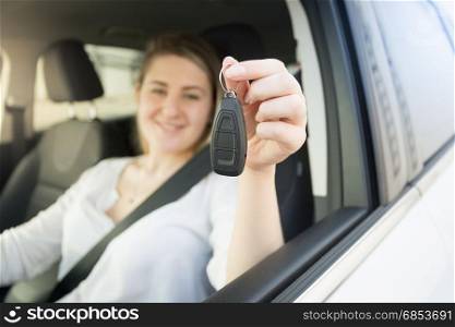 Closeup photo of young woman driving car and showing car keys