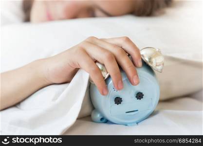 Closeup photo of young woman holding hand on alarm clock