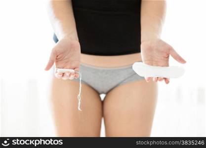 Closeup photo of young woman holding hygiene pad and tampon