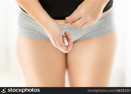 Closeup photo of young woman in lingerie holding hygienic tampon