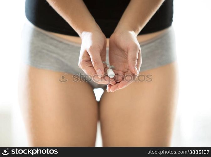 Closeup photo of young woman in panties holding cotton menstrual pad