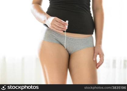 Closeup photo of young woman in panties holding hygiene tampon