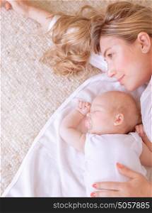 Closeup picture of beautiful young mother lying down with her sweet sleeping newborn child, loving family, new life concept