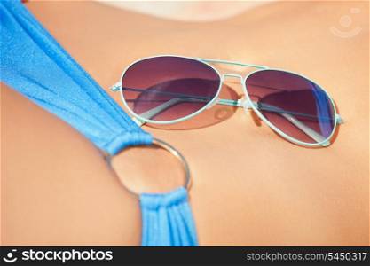 closeup picture of female belly, bikini and shades.