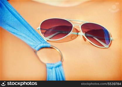 closeup picture of female belly, bikini and shades