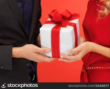 closeup picture of man and woman&#39;s hands with gift box