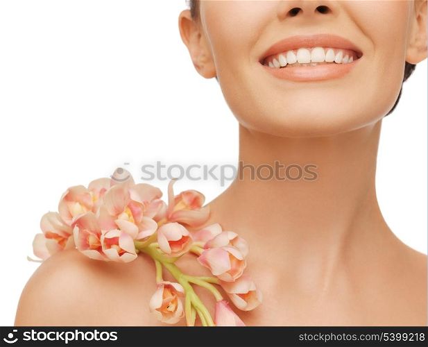 closeup picture of smiling woman with orchid flower on her shoulder