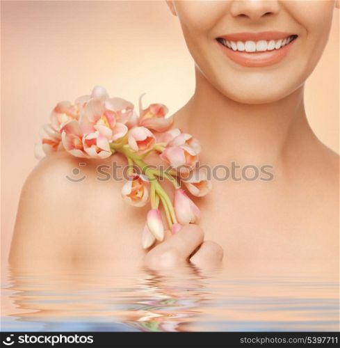 closeup picture of woman&#39;s shoulder and hands holding orchid flower