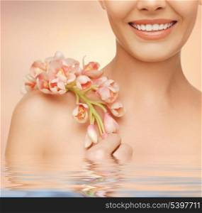 closeup picture of woman&#39;s shoulder and hands holding orchid flower