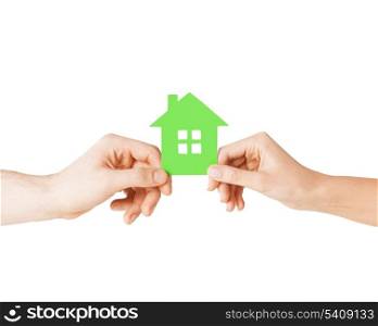 closeup picture of woman and man hands holding green house
