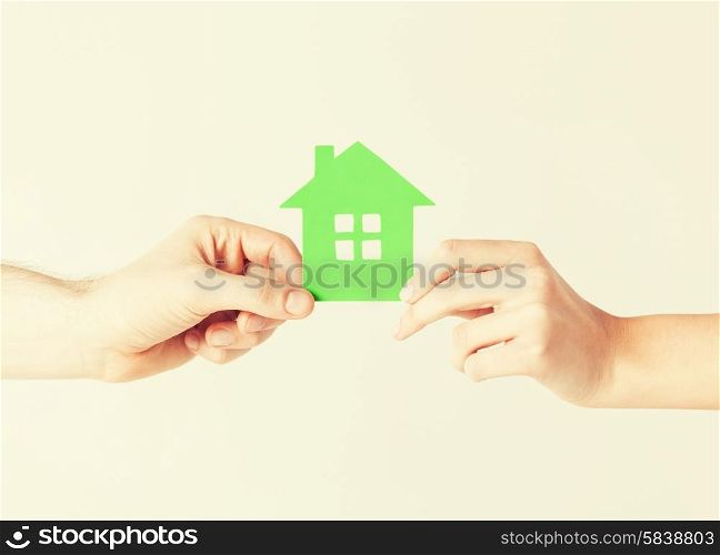 closeup picture of woman and man hands holding green house