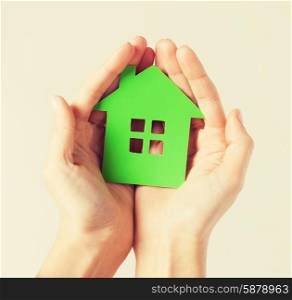 closeup picture of woman hands holding green house. hands holding green house