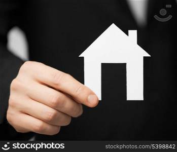 closeup pisture of man in suit holding paper house