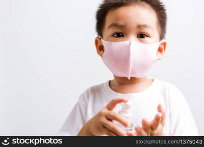 Closeup portrait Asian little child boy holding show bottle pump dispenser sanitizer alcohol spray hand wash cleaning, COVID-19 or coronavirus protection concept, isolated on white background