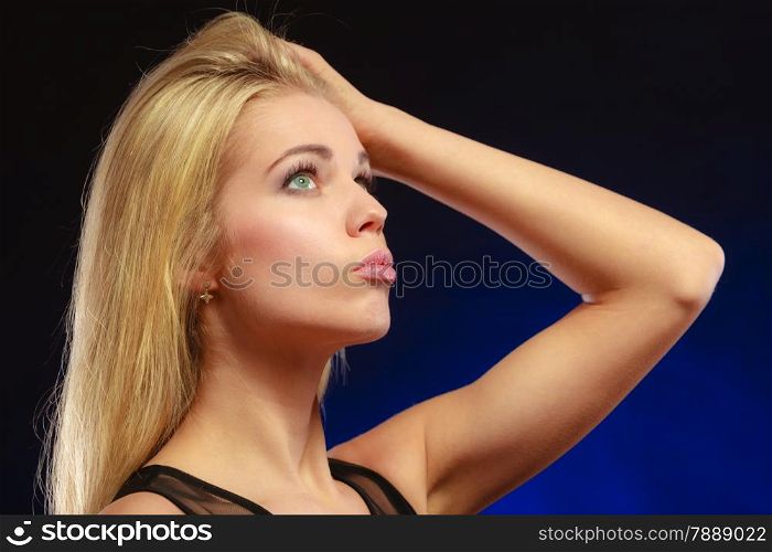 Closeup portrait attractive thoughtful woman, blonde long hair girl looking up dreaming, face profile dark blue background