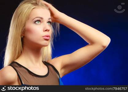 Closeup portrait attractive thoughtful woman, blonde long hair girl looking up dreaming dark blue background