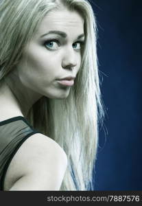 Closeup portrait attractive young woman face, allurgin girl blond long hair on dark blue background. Female beauty.