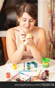 Closeup portrait brunette girl painting easter egg at home