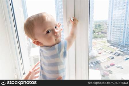 Closeup portrait fo 9 months old baby pulling window handle. Portrait fo 9 months old baby pulling window handle