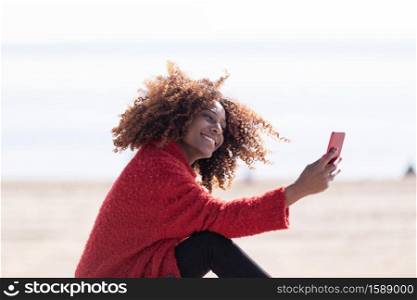 Closeup portrait of a beautiful african american woman sitting outdoors taking selfie