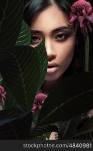 Closeup portrait of a beautiful Asian woman with plant leaves.