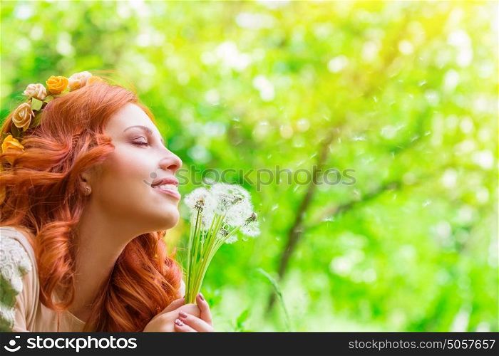 Closeup portrait of a beautiful cheerful female holding in hands dandelion flowers, enjoying beauty of spring nature