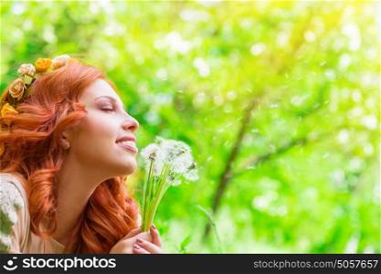 Closeup portrait of a beautiful cheerful female holding in hands dandelion flowers, enjoying beauty of spring nature