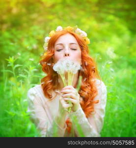 Closeup portrait of a beautiful dreamy female holding in hands dandelion flowers and with closed eyes blowing on it, enjoying beauty of spring nature