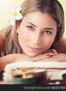Closeup portrait of a beautiful woman at spa salon, lying down on the massage table, health care and beauty treatment
