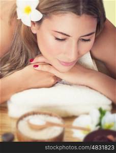 Closeup portrait of a beautiful woman at spa salon, lying down on the massage table, health care and beauty treatment