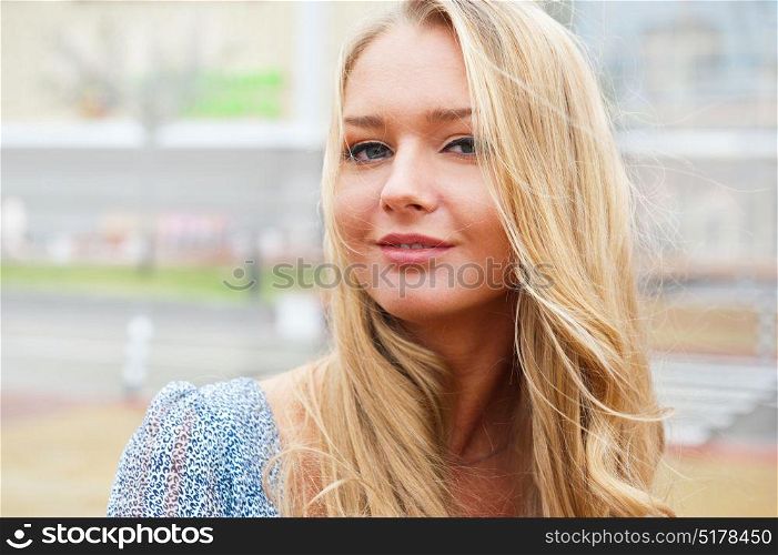 Closeup portrait of a beautiful woman in the city at summer time with modern building at the background