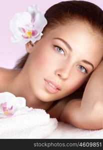 Closeup portrait of a beautiful woman with orchid flower in hair, lying down on massage table, spending wonderful day at spa, happy healthy lifestyle