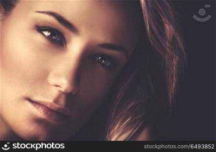 Closeup portrait of a beautiful woman with perfect nude makeup on dark background, gorgeous photoshoot of attractive model. Fashion woman portrait