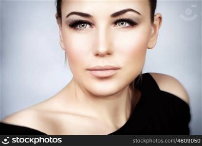 Closeup portrait of a beautiful woman with stylish makeup over gray background, smoky eyes and perfect skin tone, gorgeous seductive model