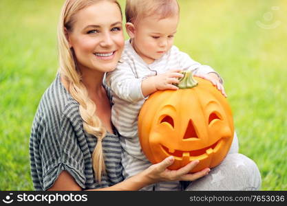 Closeup portrait of a beautiful young mother with her precious little son preparing to his first Halloween holiday, playing with pumpkin, family fun