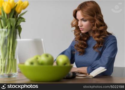 Closeup portrait of a beautiful young redhead woman working using laptop at her desk at office