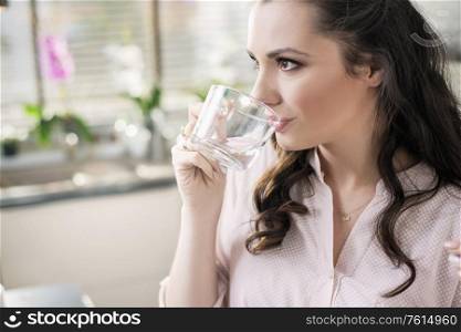 Closeup portrait of a brunette woman drinking still water