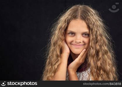 Closeup portrait of a cheerful ten year old girl on black background