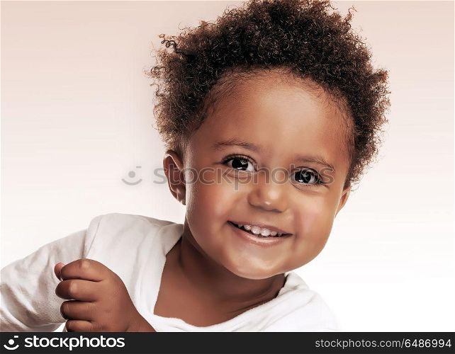 Closeup portrait of a cute little african american boy isolated on beige white background, sweet kid having fun in the studio, happiness and carefree childhood concept. Cute little boy