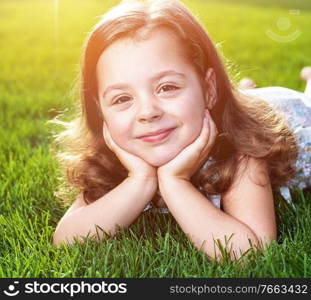 Closeup portrait of a cute little child lying on a fresh lawn