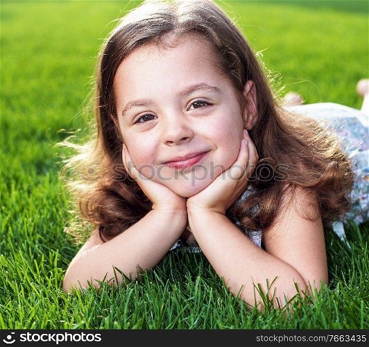 Closeup portrait of a cute little child lying on a fresh lawn
