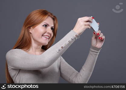 Closeup portrait of a cute young woman talking on mobile phone against grey background