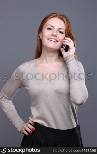 Closeup portrait of a cute young woman talking on mobile phone against grey background