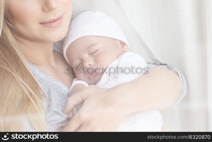Closeup portrait of a gentle mother holding in hands her newborn sleeping baby, happy domestic life, family love concept