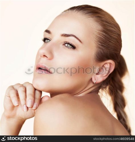 Closeup portrait of a gorgeous seductive female with natural makeup and scythe hairstyle isolated on a beige background, authentic beauty
