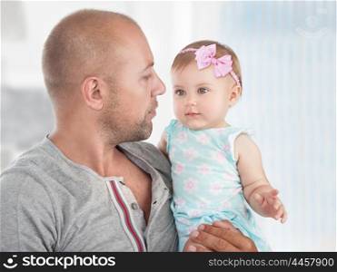 Closeup portrait of a handsome dad with cute little daughter on hands, spending time at home, happy fathers day theme