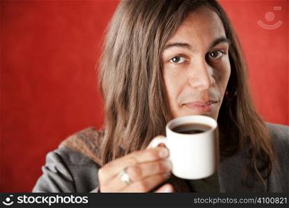Closeup Portrait of a Handsome Young Man with Long Hair Drinking Coffee